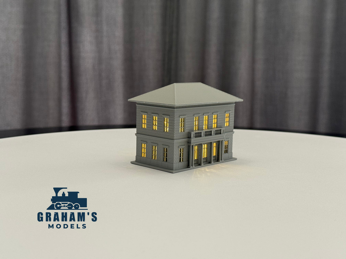 Detailed view of Graham’s Models small N scale train station with platform, building, and surrounding tracks in a model railway setup.